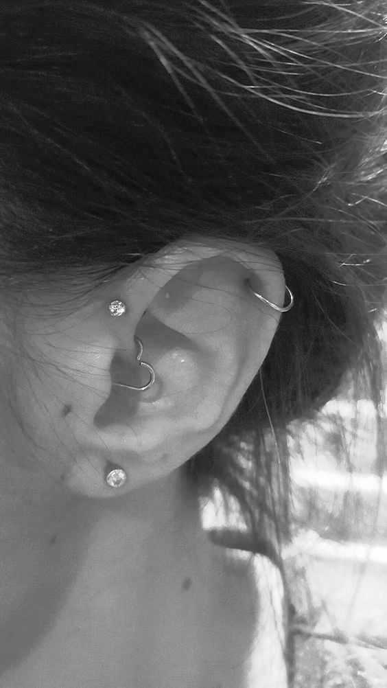 a daith, forward helix, upper helix and lobe piercing, with studs and heart-shaped earrings