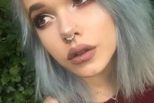 a double nose piercing with studs, a septum piercing with an embellished ring and a vertical lip piercing