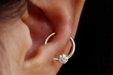 a flat piercing with a mother of pearl stud and a snug plus lobe piercing with a gold hoop with a diamond