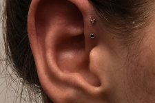 a gold stud and a hoop in the lobe and a gold and black stud in the forward helix