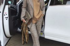 a grey plaid pantsuit, a camel turtleneck with a brooch, green shoes and a printed bag