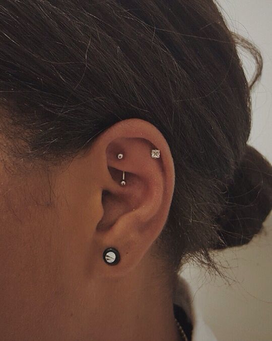 a lobe, helix and rook piercing done with various silver and diamond studs