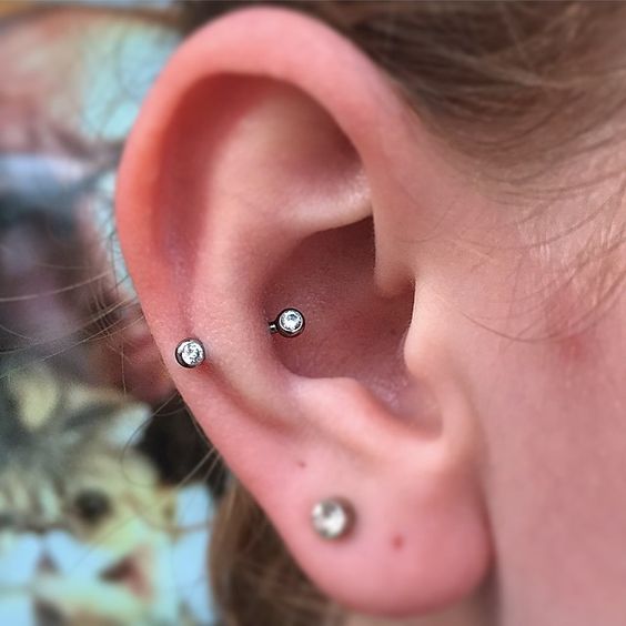 a lobe piercing and a snug piercing with matching silver and Swarovski crystals are chic