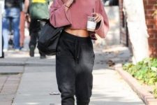 a pink cropped sweatshirt, black joggers, black lacquer boots and a black tote