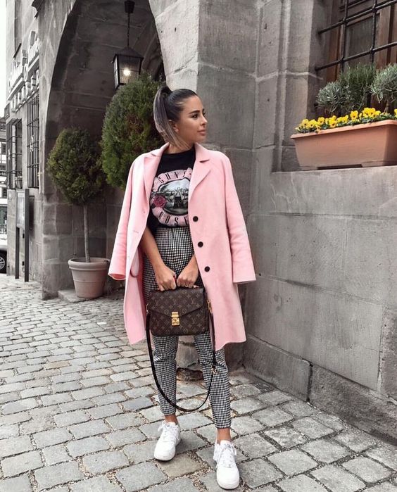 a printed black tee, plaid pants, a pink short coat, white sneakers and a brown printed bag