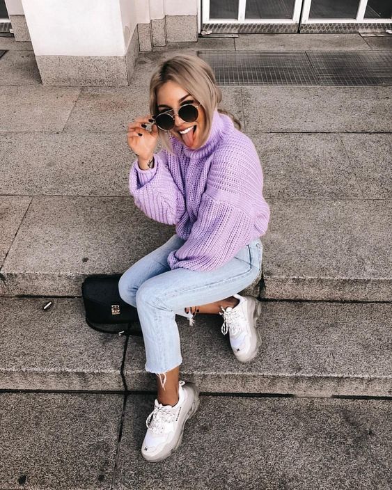 a purple chunky knit sweater with a turtleneck, blue cropped jeans and white trainers plus a black bag
