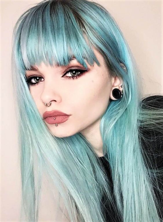 a septum piercing with a ring, a vertical labret piercing, tunnel piercing and blue hair