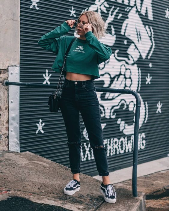 a sexy outfit with a green cropped sweatshirt, black ripped jeans, black sneakers, a black bag
