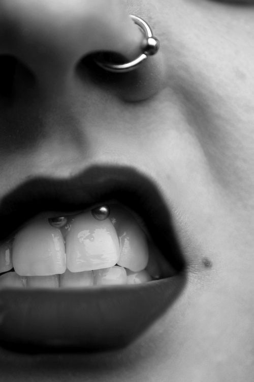 a smiley piercing done with a barbell and a nose piercing with a rhinestone ring jewelry piece