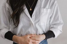 a trendy casual look with a black turtleneck, a white shirt, blue jeans and a necklace