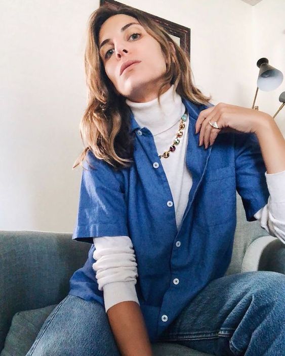 a white turtleneck, a bright necklace, a blue shirt and jeans for a casual and chic look