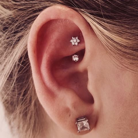 an oversized diamond stud and a little shiny star and stud rook piercing