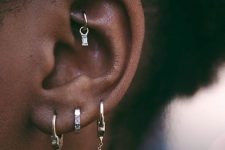 layered piercings including a catchy diamond hoop in the rook look very boho and glam