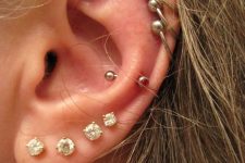 multiple lobe piercings with matching studs and a snug piercing with a red rhinestone earring