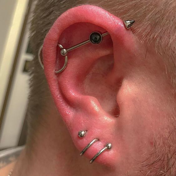 three lobe piercings plus an industrial one with a bold bar with a rhinestone and a circle