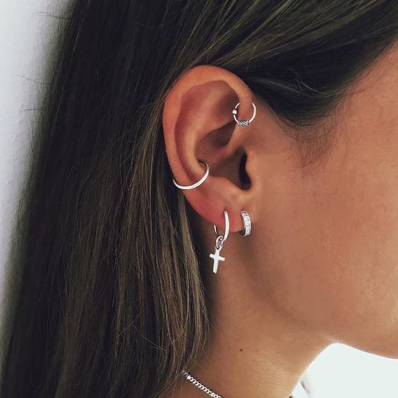 two silver earrings in the lobe, a conch hoop and a mini hoop in the forward helix