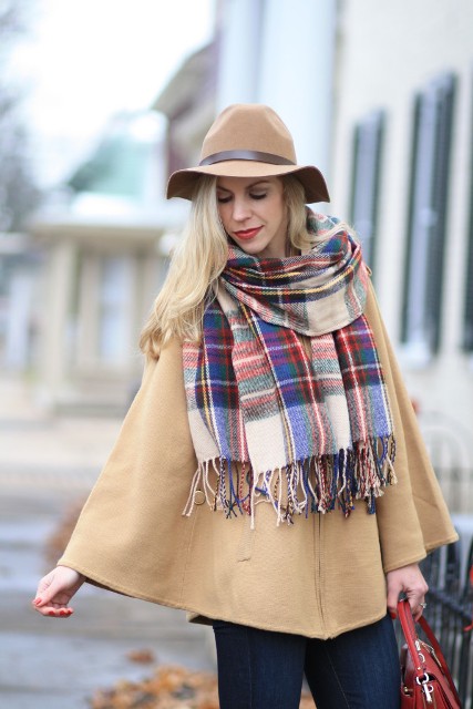 With beige cape coat, hat, red bag and jeans