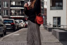 With black loose sweater, red bag, white sneakers and red framed sunglasses