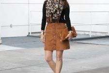 With black shirt, brown mini skirt, clutch and black boots