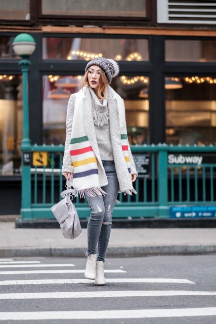 With gray sweater, gray coat, hat, gray bag, heeled boots and distressed jeans