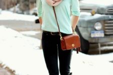 With mint green shirt, black pants, brown crossbody bag and brown and black high boots