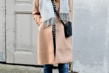 With striped shirt, beige coat, jeans, black bag and black ankle boots