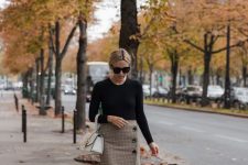 a black long sleeve top, a tweed skirt on buttons, black sock boots and a white bag for fall