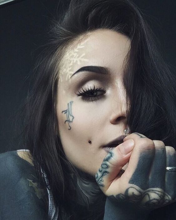 a cheek piercing plus a medusa one for a bold and mysterious look plus a face tattoo