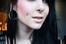 a double cheek piercing, a septum and a lip piercing with matching jewelry plus large tunnels