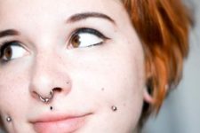 a double cheek piercing, a septum piercing, medusa and a nose piercing for a bold look