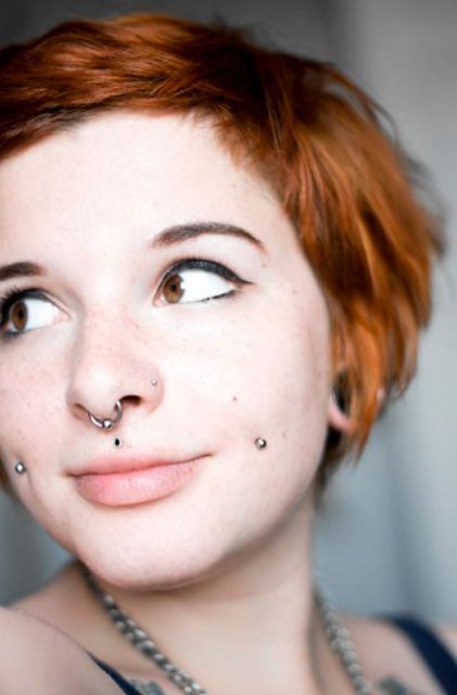 a double cheek piercing, a septum piercing, medusa and a nose piercing for a bold look