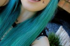 a double cheek piercing plus a septum one and blue hair for an extra bold look that stands out