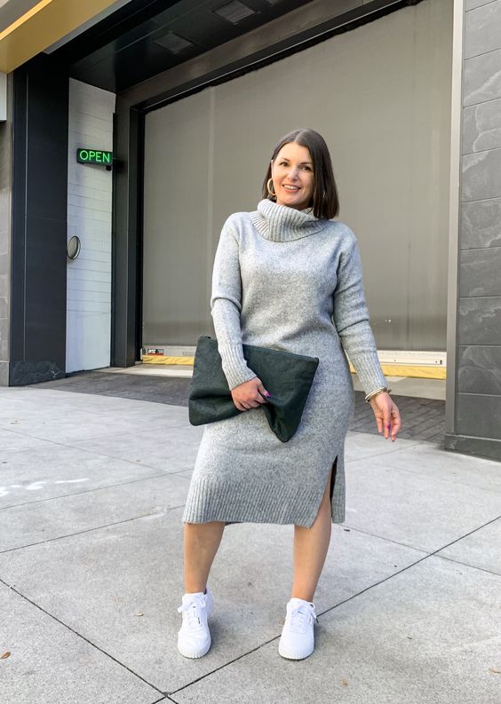 a grey fitting sweater dress with side slits, white sneakers and a black oversized clutch