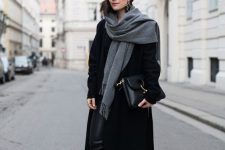 a monochromatic outfit with black leather leggings, trainers, a midi coat, a bag, a beanie and a grey scarf