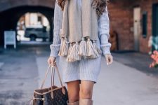 a short grey sweater dress, tan knee boots, a tan scarf with oversized tassels and a black bag