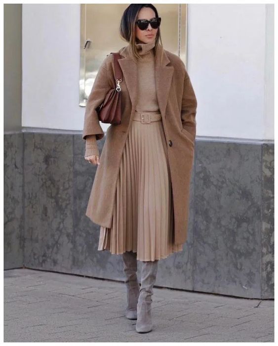 a tan turtleneck, a tan pleated midi skirt, grey boots, a brown midi coat and a brown bag