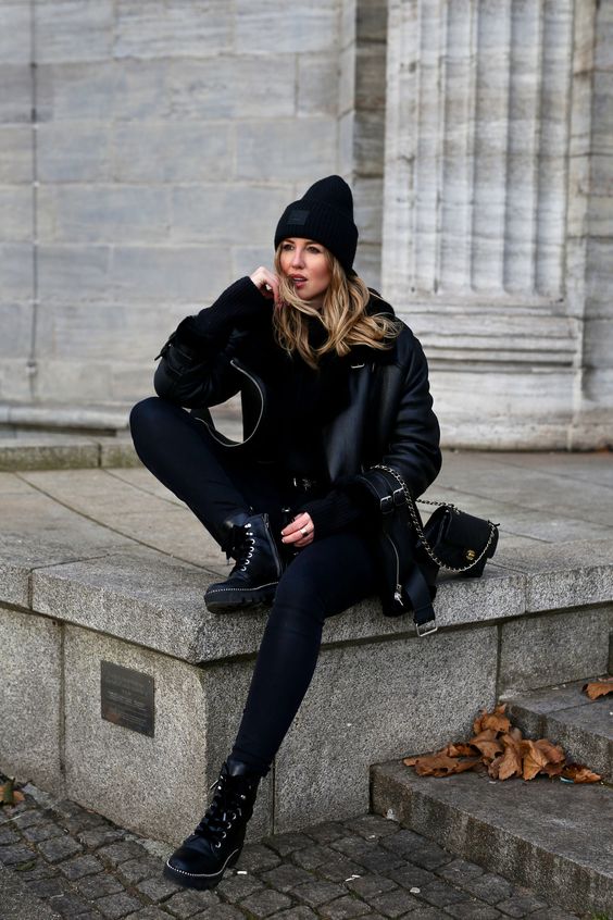 a total black outfit with skinnies, a sweater, a shearling coat, a bag and boots plus a beanie