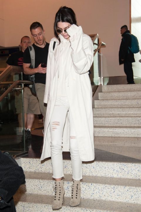 Kendall Jenner wearing a white cashmere hoodie, white skinnies, a white coat and tan booties