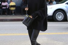 Kendall Jenner wearing black leather leggings, an oversized sweater, a black bag and black and red trainers
