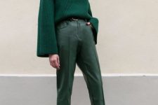 With emerald green leather cropped trousers, black high heeled boots and belt