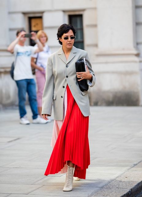 With red and pale pink pleated maxi dress, gray long blazer and clutch