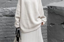 a beautiful outfit with an oversized white sweater, a pleated midi skirt, black sock boots and an oversized bag