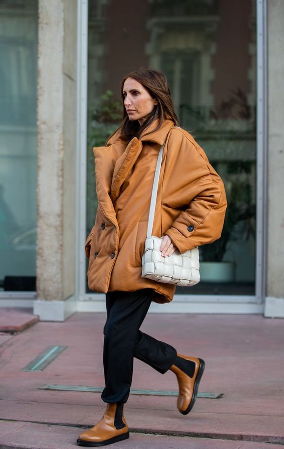 a bold look with a cognac leather puff coat, black trousers, cognac chelsea boots and a white woven bag