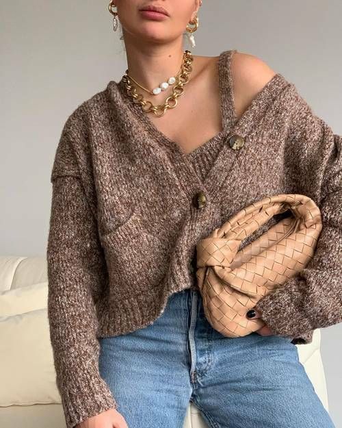 a brown knit top and a matching cardigan with pockets, blue jeans and a woven beige bag plus layered necklaces