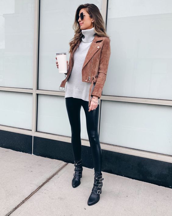 a chic look with an oversized grey sweater, black leather leggings, boots and an ocher suede moto jacket