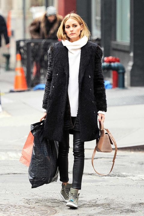 a comfortable winter look with black leather leggings, an oversized white sweater, grey trainers, a faux fur coat and a tan bag