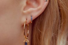 a gold hoop earring with a sapphire, a small sapphire earring and some matching cuffs