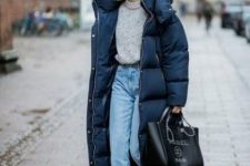 a grey chunky sweater, blue jeans, emerald velvet boots, a navy midi puffer coat and an oversized black bag