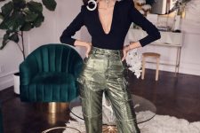 a jaw-dropping holidya look with a black top with a plunging neckline, metallic green pants, black shoes and statement earrings