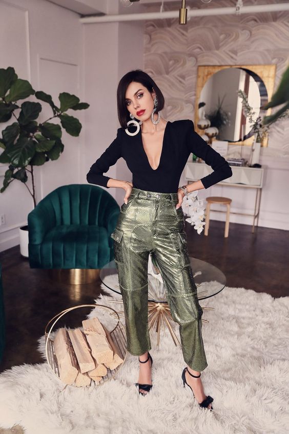a jaw dropping holidya look with a black top with a plunging neckline, metallic green pants, black shoes and statement earrings